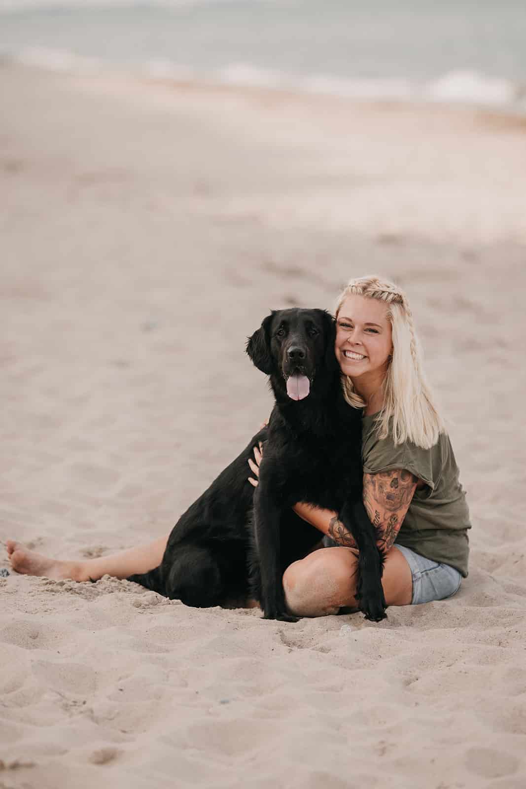 Woman hugging a black dog on the beach