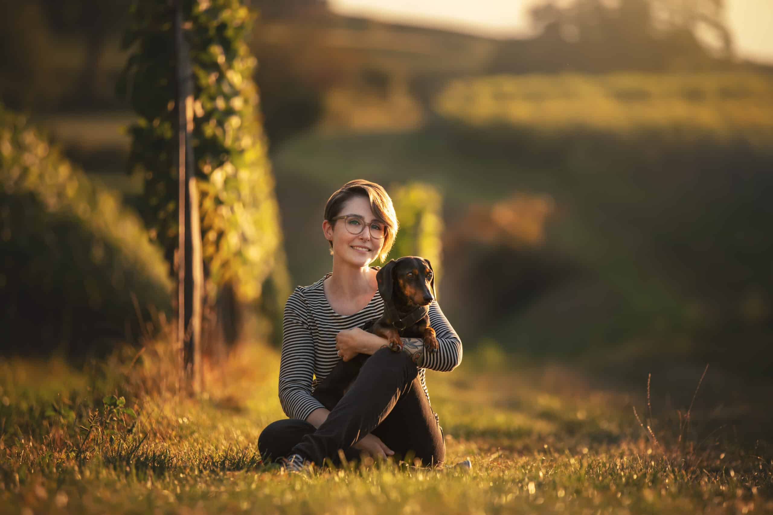 Woman sitting in grass with a small dog